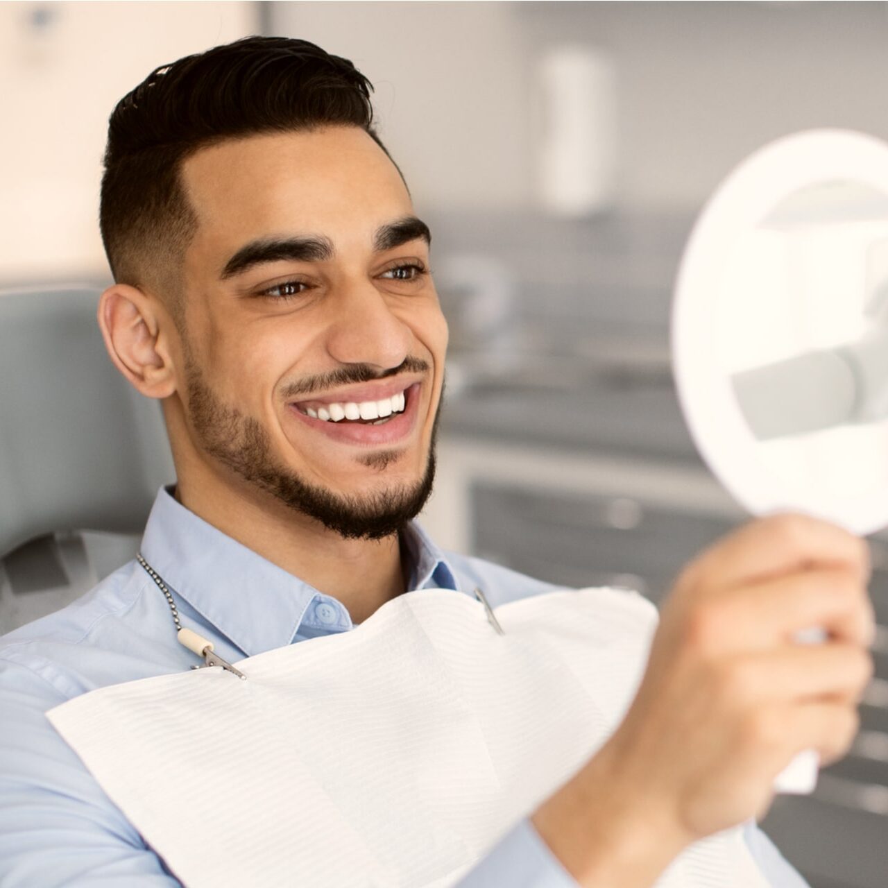 Happy Handsome Man Looking To Mirror After Teeth Treatment