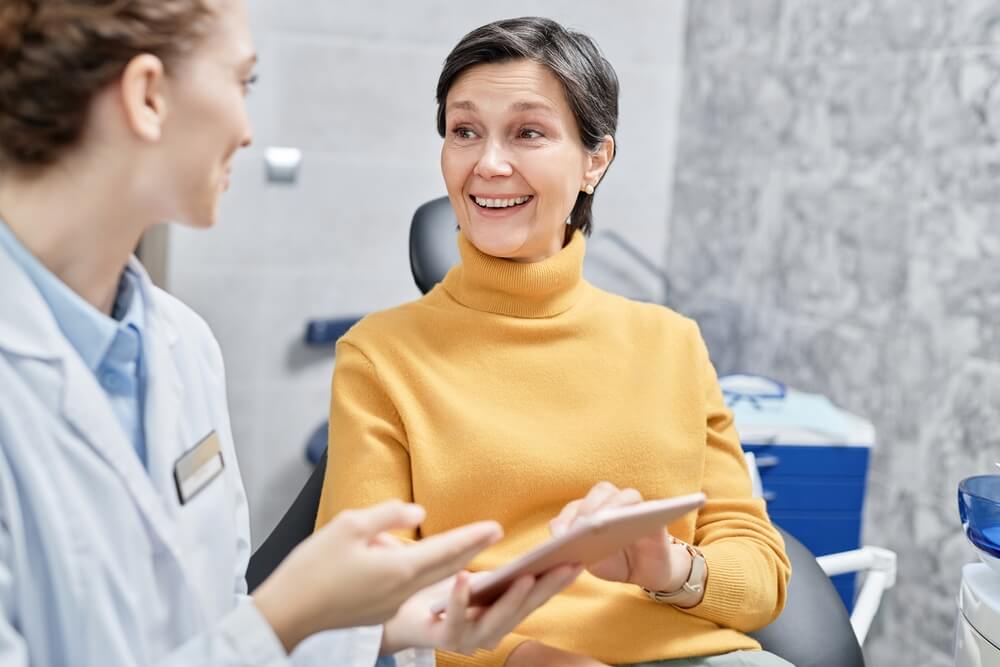 smiling mature woman in dental clinic talking to female dentist