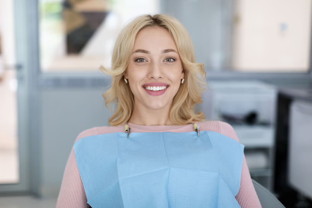 Young woman patient sitting in dental chair and smiling