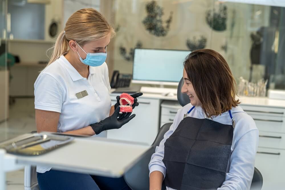 woman dentist shows on a model of the jaw how to properly brush the teeth