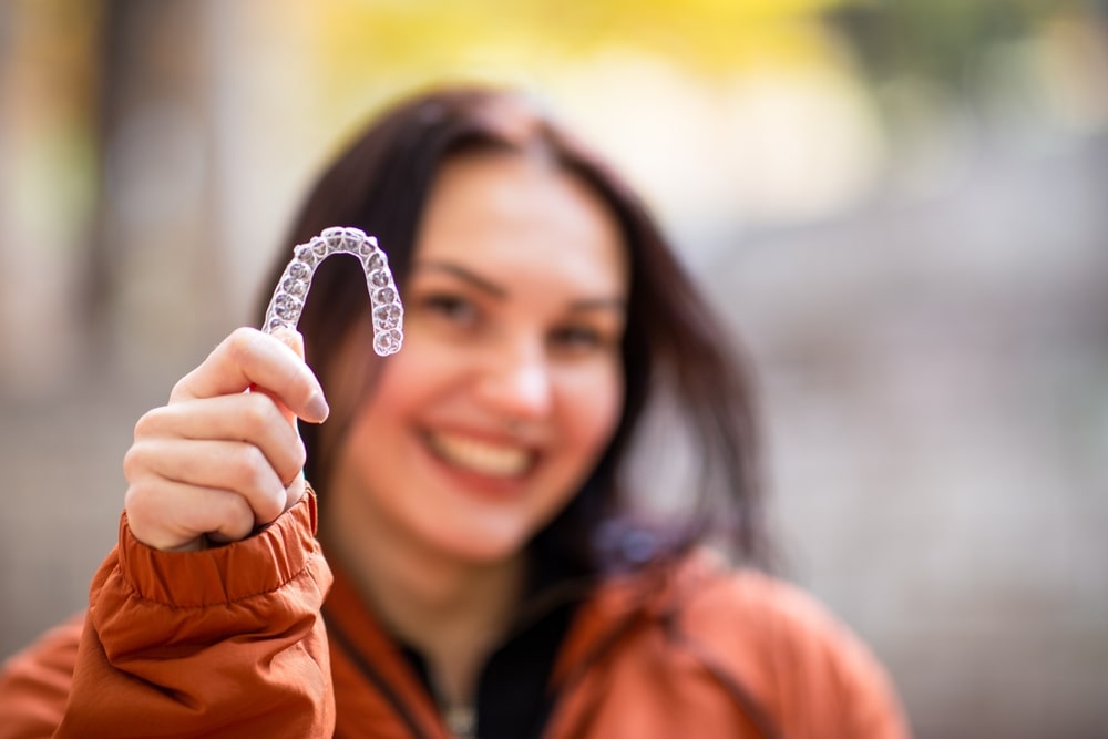 Happy young woman smiling with invisible teeth aligner