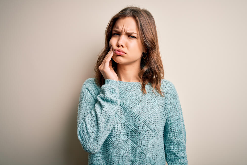 girl touching mouth with hand with painful expression