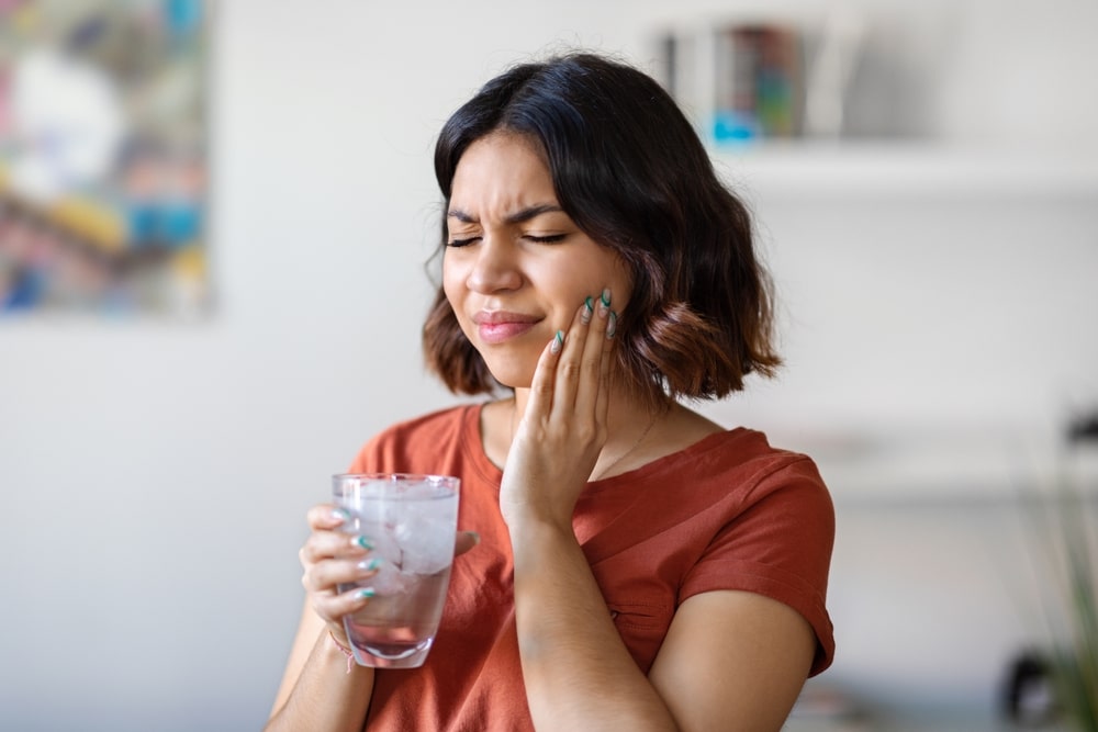 woman drinking water with ice and touching her cheek
